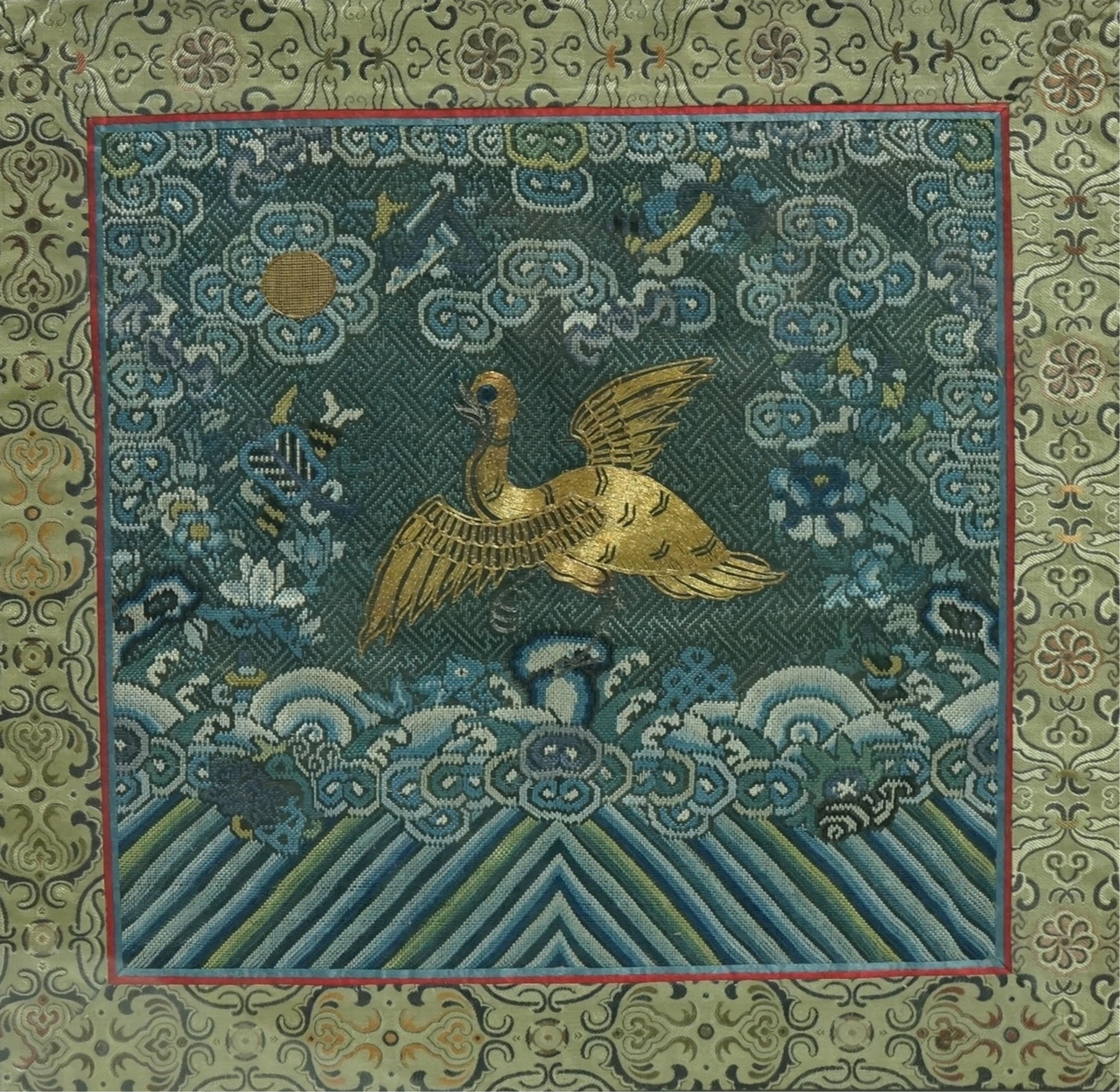 A framed late 19th early 20th century Chinese Mandarin Rank Badge. Worked with a gold thread central motif of a Phoenix, surrounded by finely silk embroidered auspicious motifs, clouds and rolling sea beneath. Bordered w